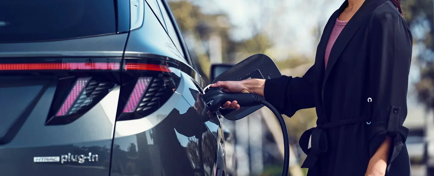 Hyundai FAQ Woman Charging Hyundai Plug-In Vehicle
