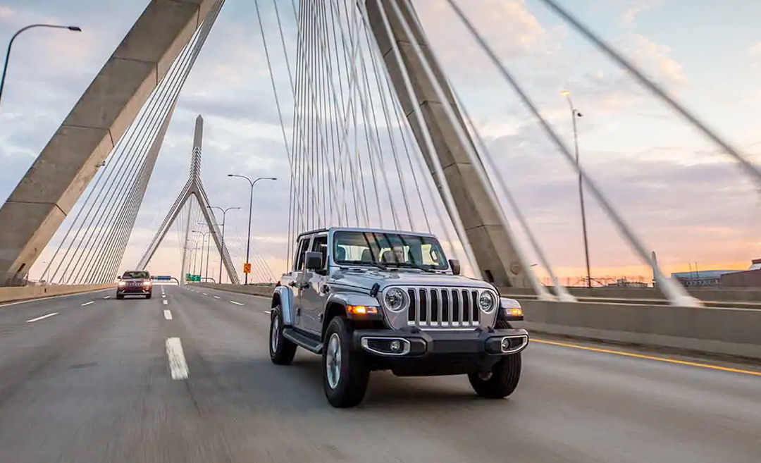 2021 Jeep Wrangler Jeep Wrangler driving across a city bridge at sunset