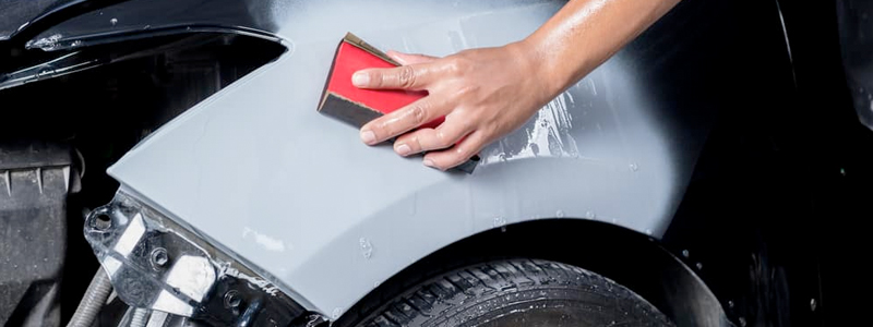 Body Shop Estimate Technician Smoothing Out Vehicle Damage